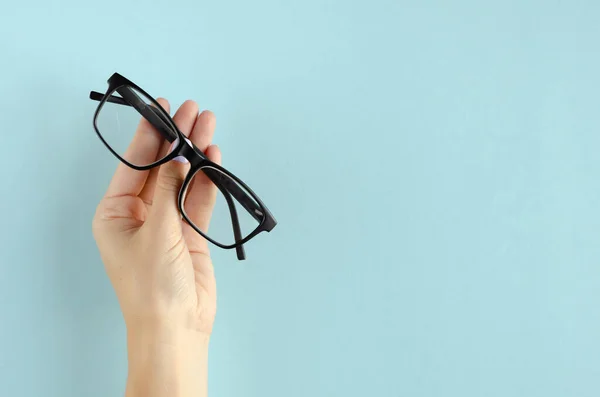 Mano con lentes composición sobre fondo azul . — Foto de Stock