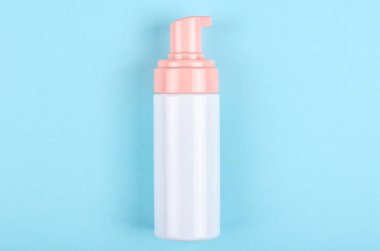 Mavi arka planda dezenfektan şişesi olan bir el. Düz, yukarıdan görüntü. Uzayı kopyala, şablon.