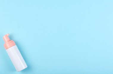 Mavi arka planda dezenfektan şişesi olan bir el. Düz, yukarıdan görüntü. Uzayı kopyala, şablon.