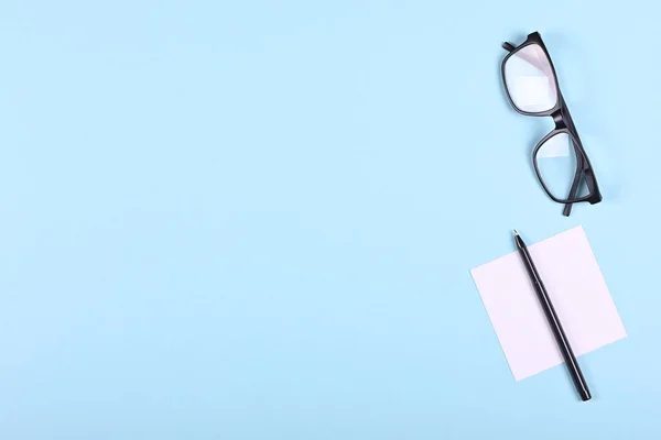 黒眼鏡 紙と青の背景組成物にペン フラットレイアウト オーバーヘッドビュー画像 — ストック写真