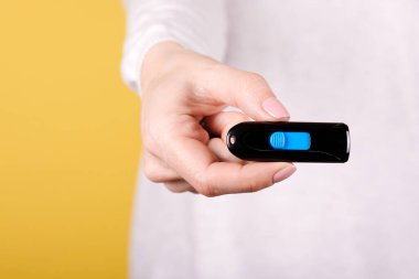 Sarı arka planda elinde siyah USB bellek var. Fotoğrafı kapat..