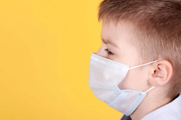 医療マスクのブルネットの少年の肖像画 サイドビュー 黄色の背景に隔離された スペースのコピー — ストック写真