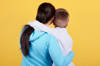 Esmer çocuk ve anne birlikte oturuyor, sarılmalar, sevgi, aile.
