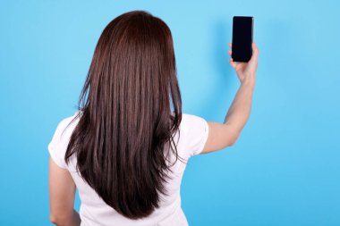 Esmer, uzun saçlı, cep telefonu kullanan, arkadan gören bir kız..