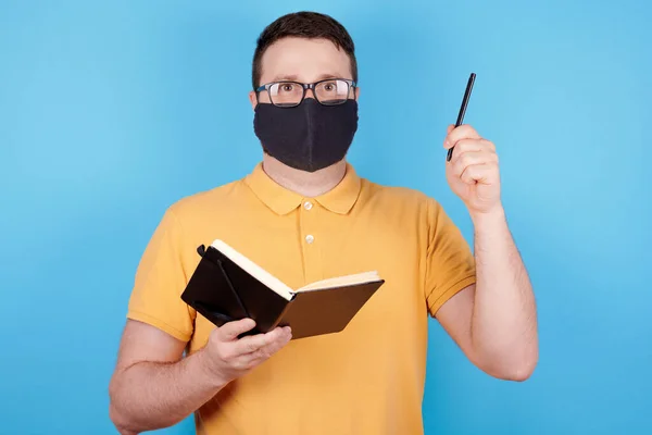 眼鏡と保護マスクのブルネットの男は ペンとノートブック アイデアのコンセプトを使用します — ストック写真