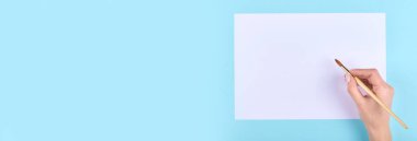 Mavi arka planda boya fırçası olan el..