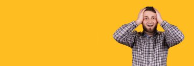 Sakallı bir adam elini tutuyor, panik halinde, turuncu arka planda izole edilmiş. Sorunlar kavramı.