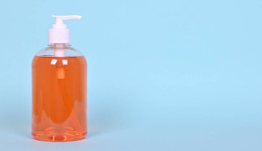 Mavi arka planda bir şişe turuncu sıvı sabun. Yüksek kalite fotoğraf