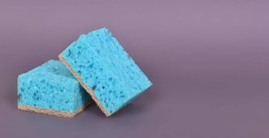 Daireyi temizlemek ve gri arka planda bulaşık yıkamak için gözenekli bir bez. Yüksek kalite fotoğraf