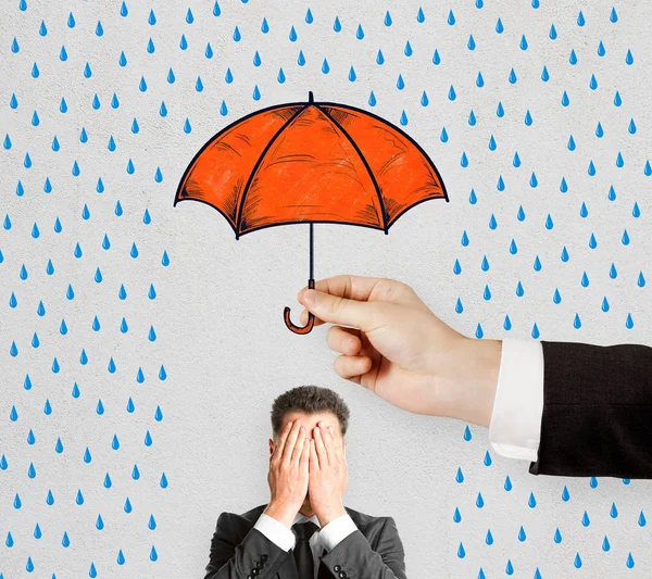 Concept of difficulty in business with hiding from rain under umbrella businessman closing his eyes by hands.