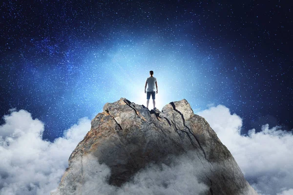 Businessman standing on abstract mountain on sky background. Promotion and leadership concep