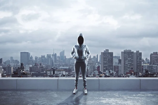 Female hacker with hood standing on rooftop with city view. Hacking and criminal concept