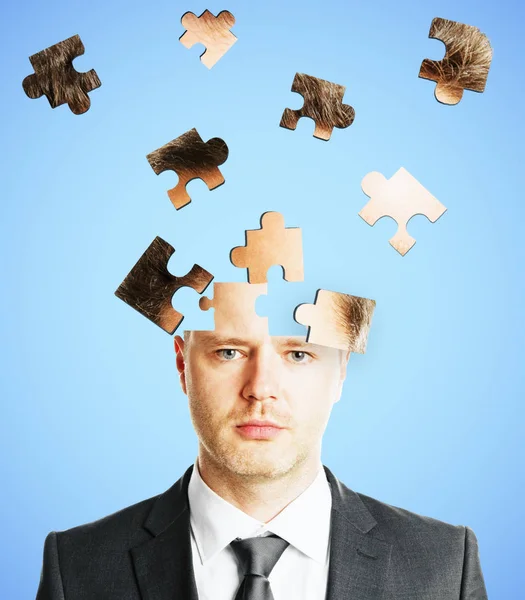 Puzzle headed businessman on light background. Confusion and challenge concept