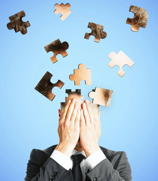 Puzzle headed businessman on light background. Confusion and jigsaw concept