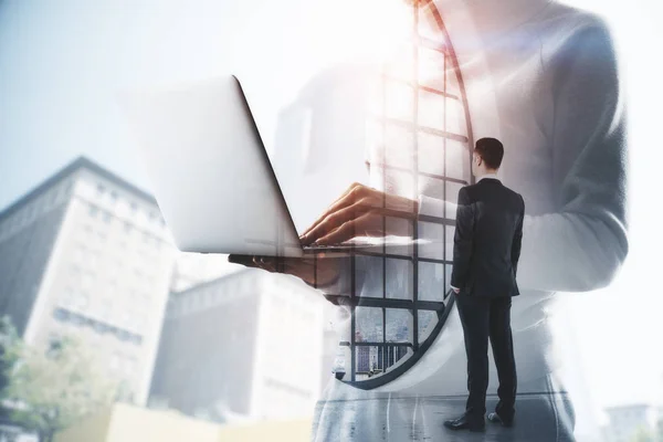 Businessman using laptop on abstract blurry office city background. Communication and network concept. Double exposure