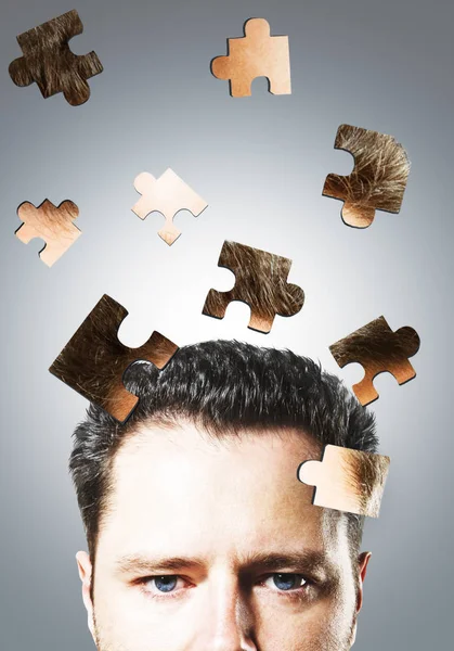 Puzzle headed businessman on gray background. Confusion and maze concept