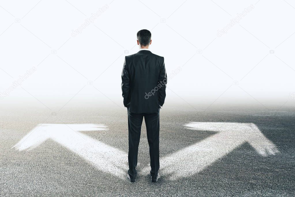 Businessman with arrows on concrete background. Different direction and future concept 
