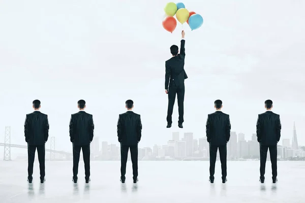 Businessmen looking at man flying with balloons. Success and leadership concept