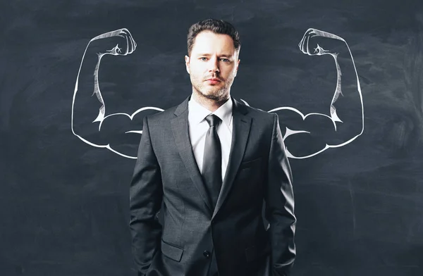 Portrait of attractive young businessman with drawn muscly arms. Confidence and strength concept