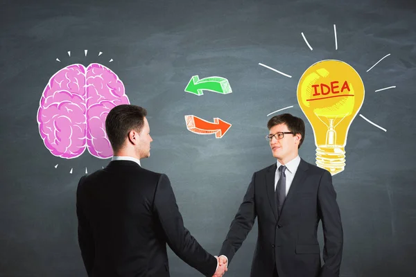 Attractive European Businessmen Shaking Hands Chalkboard Background Drawn Brain Lamp — Stock Photo, Image