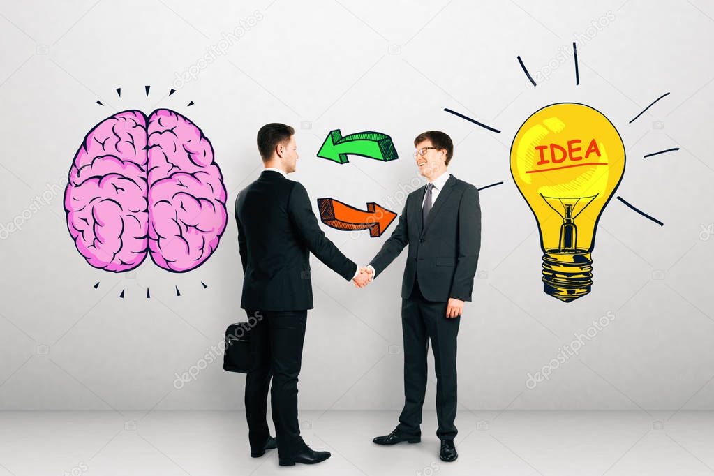 Attractive european businessmen shaking hands on concrete background with drawn brain and lamp. Brainstorm, teamwork and innovation concept 