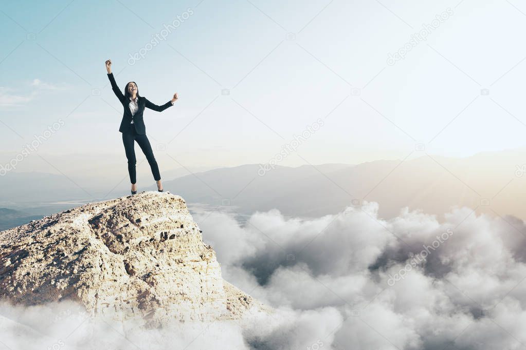 Happy businesswoman on cliff with clouds and copy space. Success and victory concept 