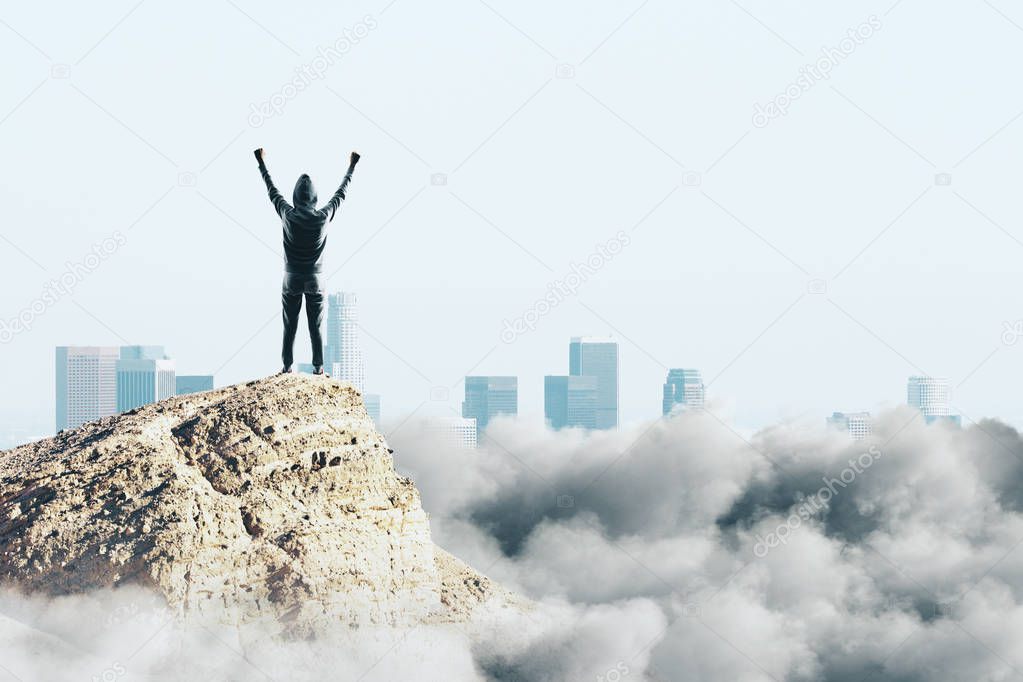 Happy hacker on cliff with clouds and copy space. Success and celebration concept 