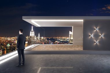 Çatı katı ve gece New York şehir manzaralı modern çatı üzerinde duran genç işadamı