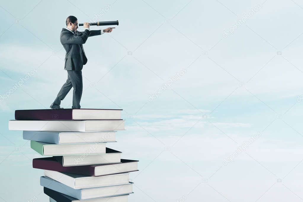 Side view of young businessman with binoculars standing on pile of books. Vision and education concept 