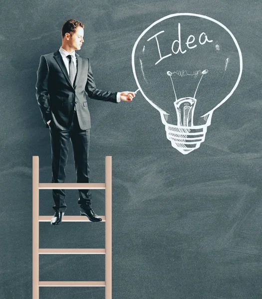 Young Businessman Standing Ladder While Drawing Idea Lamp Chalkboard Wall — Stock Photo, Image