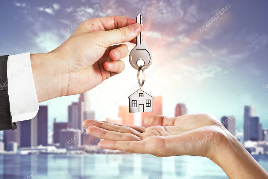 Businessman handing key on city background. Real estate and agent concept