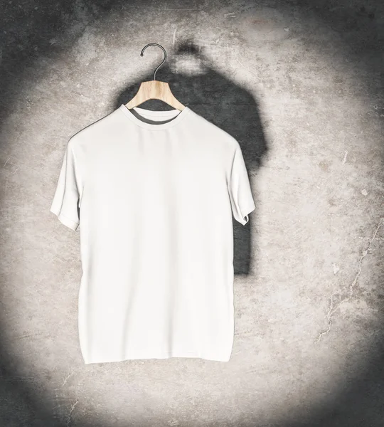 Clean white t-shirt in spotlight hanging on concrete wall. Mockup and fashion concept. 3D Rendering