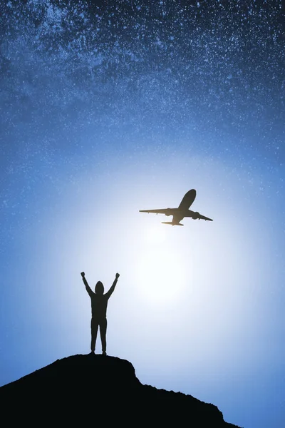 Person and airplane silhouette on hill and blurry night sky background. Success and travel concept