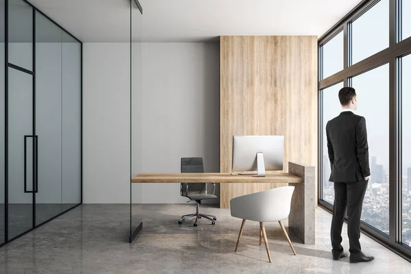 Podnikatel v moderní kanceláři s betonovým podlahovým a dřevěným stolem. — Stock fotografie