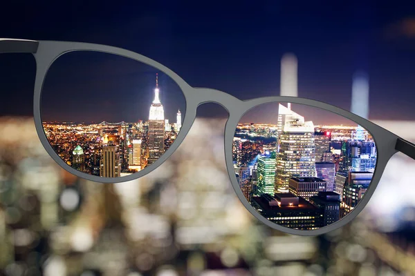 Upplyst natt stadsutsikt genom glasögon — Stockfoto