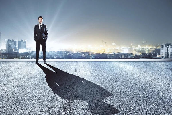 Success, vision and future concept. Side view of businessman standing on rooftop skyscraper with shadow.