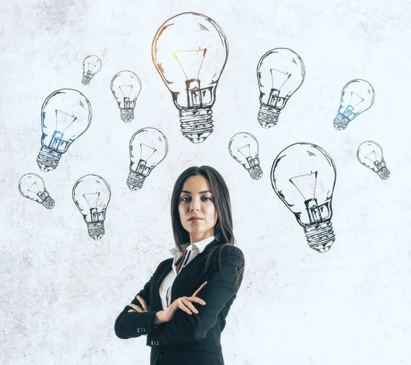 Young businesswoman in suit and drawing light bulbs over head. Success and startup concept.