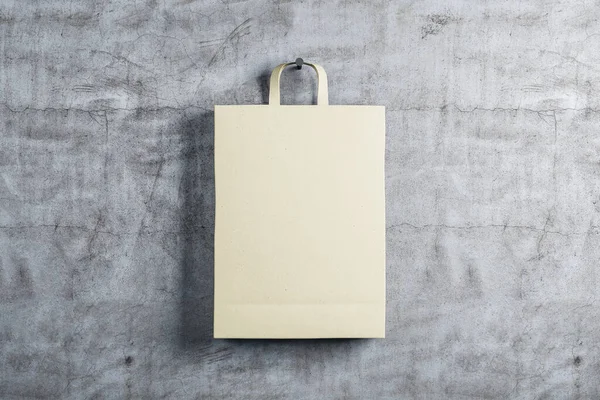 One paper shopping bag on concrete wall background. Trade and gift concept. 3D Rendering