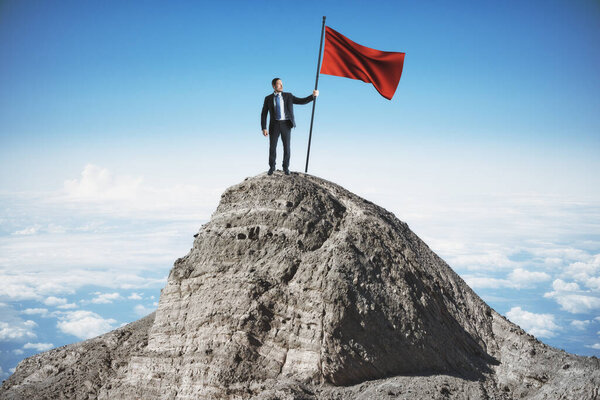 Businessman with flag standing on mountain top. Sky background. Leadership and victory concept