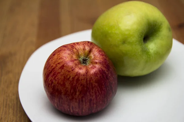 Red green Apple on a white plate. In section.