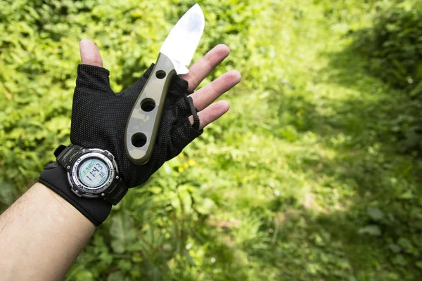 A gloved hand with a watch And a knife. knife in hand. Gloved hand.
