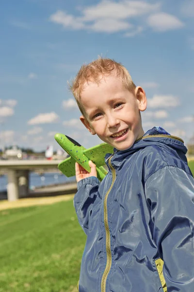 Un chico con chaqueta lanza un avión de espuma . — Foto de Stock