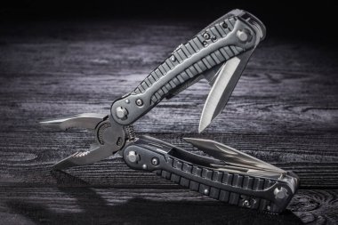 Multitool on a dark wooden background. clipart