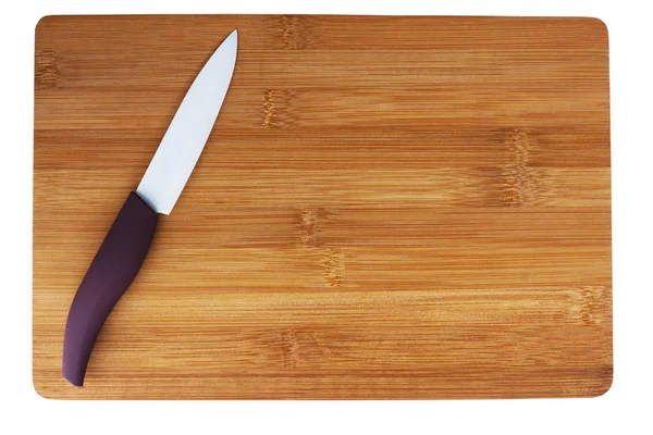 Cuchillo de cerámica con una pluma púrpura en la tabla de cortar . —  Fotos de Stock