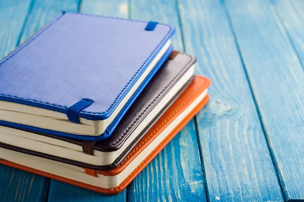Papelaria, caderno e caneta em um fundo de madeira azul . — Fotografia de Stock