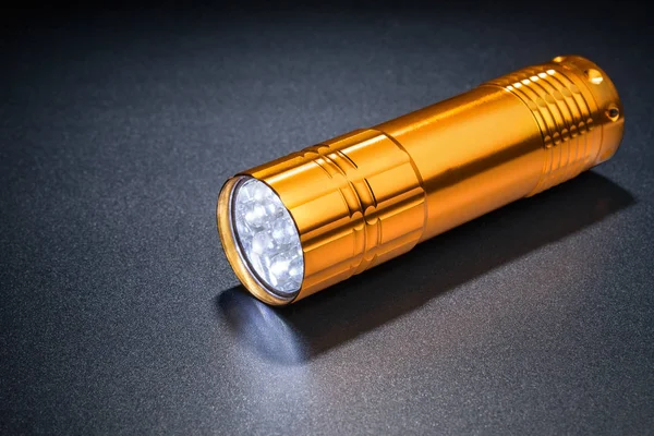 Pocket LED light on a dark surface.