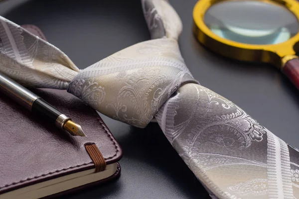 ' Ντρας ακόμα ζωή. Μια πένα με ένα σημειωματάριο βρίσκεται σε μια γραβάτα. — Φωτογραφία Αρχείου