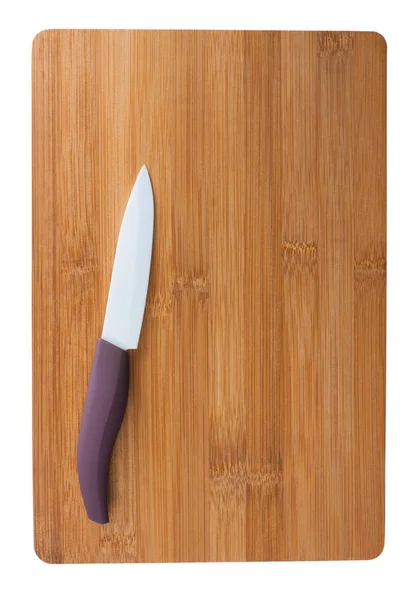 Cuchillo de cerámica con una pluma púrpura en la tabla de cortar . —  Fotos de Stock