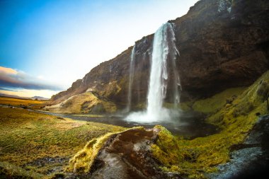 Seljalandsfoss, a waterfall with a small cave behind it in the south region in Iceland, it is part of the Seljalands River that has its origin in the volcano glacier Eyjafjallajokull clipart