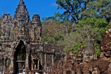 Efsanevi heykellerin sol tarafındaki efsanevi bir yılanın (Naga) başını çekerek Angkor Thom (Büyük Şehir), Siem Reap, Kamboçya 'nın güney kapısına giden hendeğin üzerinden geçiyorlar.
